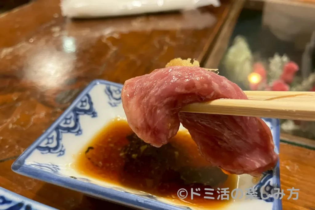 馬刺しをショウガ醤油に付けて食べるところ