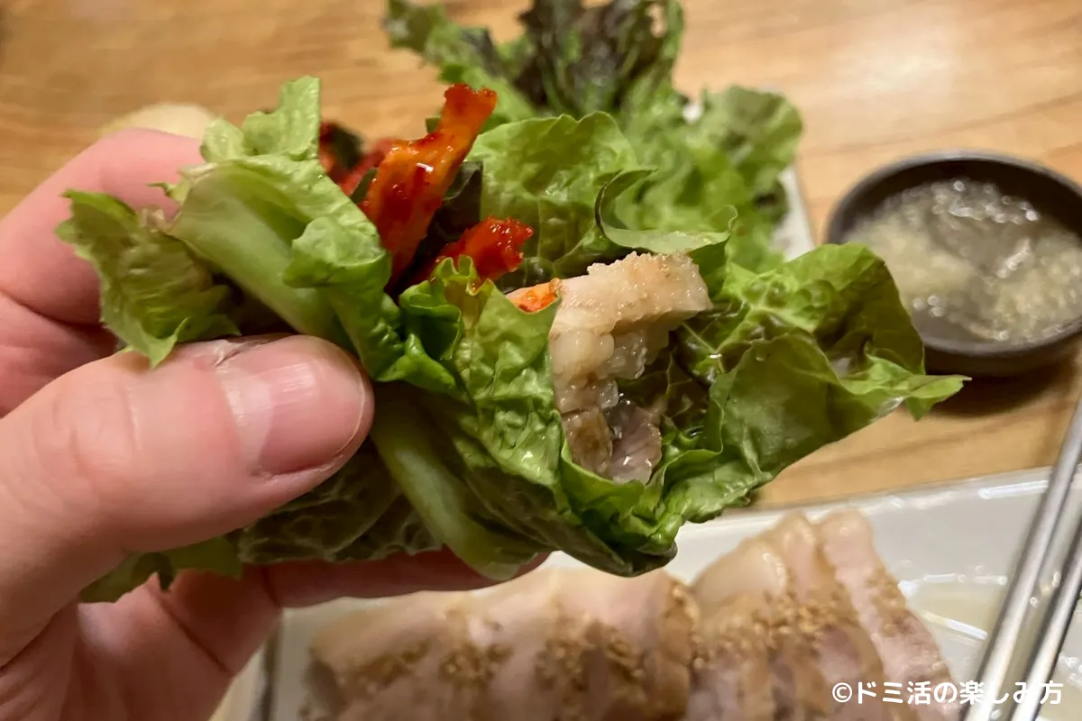 仁寺洞マヌルポッサムで豚肉をサンチュで包んで食べようとしている写真